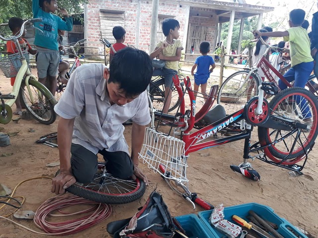 Dù đôi chân không còn lành lặn nhưng anh Dũng luôn vào bản sửa xe miễn phí cho học sinh nghèo. Ảnh: Dân Trí